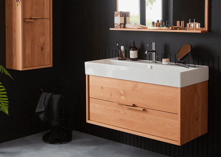 Un baño con paredes negras y un tocador de madera.